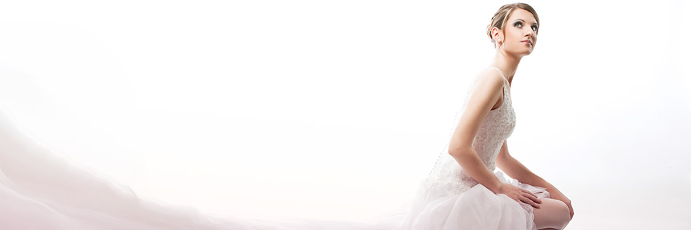 A bride kneeling in a beaded gown with a long soft train