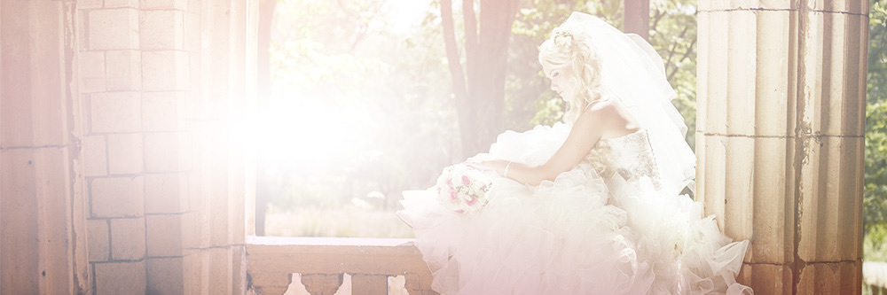 A bride in a full tulle gown sitting in a sunlit window